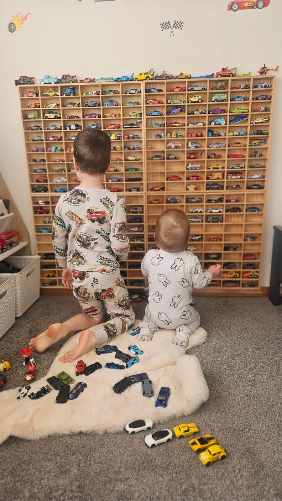 Four JCAR 60 racks mounted side by side on one wall, two children choosing cars from them