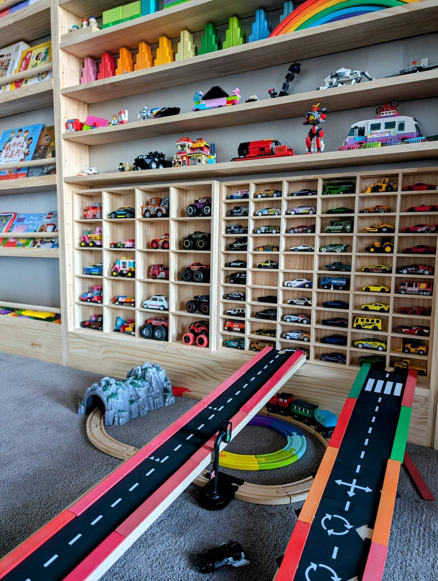 Two JoyKids diecast racks side by side on the bottom tier of a JORA 7 shelf, toys and books displayed on the tiers above