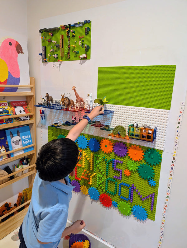 A child adding a gear to the baseplate on his playroom wall