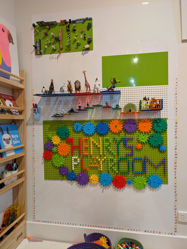 The finished playroom wall — marker decal, magnetic baseplates, gears and a shelf of figures
