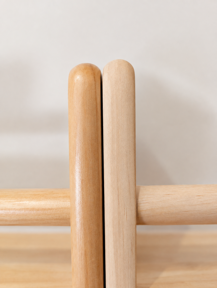 Close-up of two rounded upright ends on a JoyKids pine shelf, one varnished and one raw, with a smooth dowel running between them